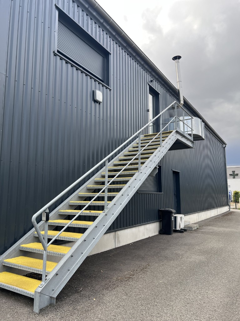 Vue rapprochée de l’escalier extérieur et de la porte en haut des marches.